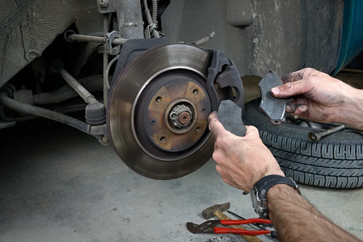Mechanic comparing worn brake pads against a disc rotor at the workshop