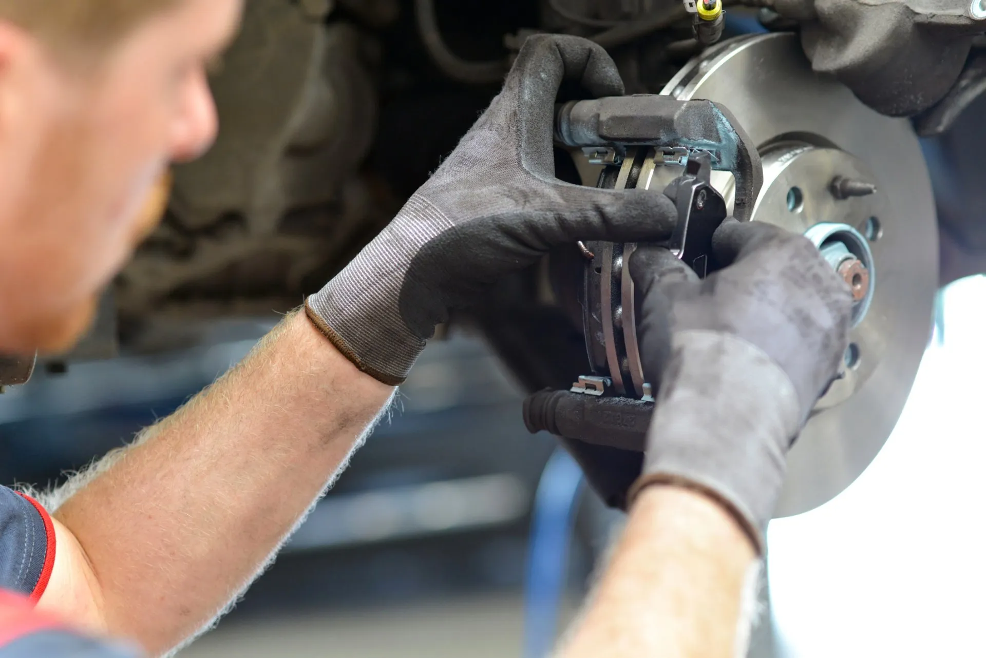 Mechanic fitting new brake pads into a front disc brake caliper